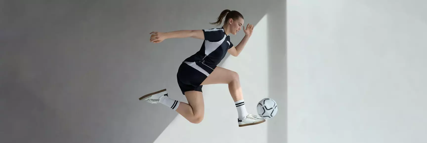 A model in the air with a soccer ball in a kick pose